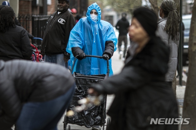 미국 내 신종 코로나바이러스 감염증(코로나19) 집중 감염지가 된 뉴욕 브루클린에서 지난 20일 한 시민이 마스크에 푸른 판초 차림으로 길을 걷고 있다. (출처: 뉴시스)