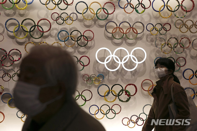[도쿄=AP/뉴시스] 23일 마스크를 낀 시민들이 일본 도쿄의 올림픽 박물관을 지나고 있다. 신종 코로나바이러스 감염증(코로나19) 확산 속도가 높아지는 가운데 국제올림픽위원회(IOC)가 오는 7월 일본에서 개최 예정된 도쿄올림픽의 취소 가능성을 제기했다. 2020.2.26.