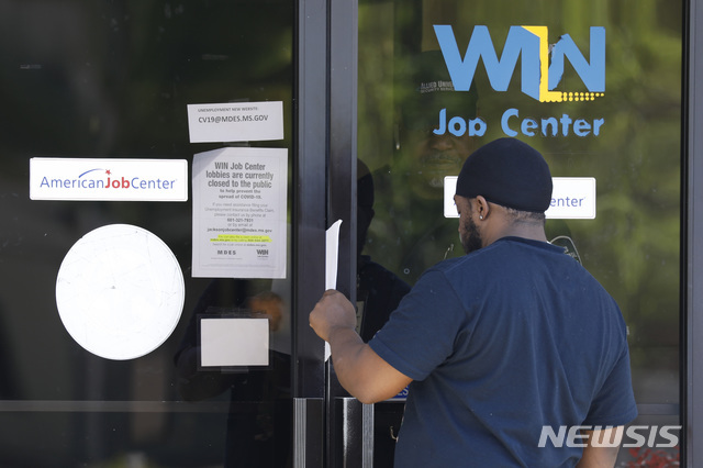 2일(현지시간) 미국 미시시피주 잭슨에 있는 주 직업 센터에서 타이론 키톤 주니어가 유리문 뒤에서 실업수당 청구 신청서를 건네받고 있다. 미 노동부는 3월 넷째주 신규 실업수당 청구 건수가 665만건을 기록했다고 밝혔다. (출처: 뉴시스)