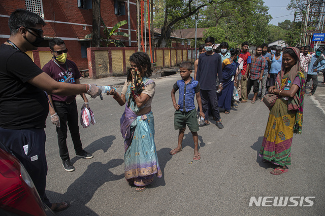 신종 코로나바이러스 감염증(코로나19) 확산을 막기 위해 인도 전국이 봉쇄된 가운데 19일(현지시간) 인도 가우하티에서 주민들이 노숙자들에게 물과 음식을 나눠주고 있다. (출처: 뉴시스)