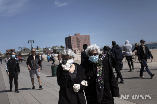25일(현지시간) 마스크와 장갑을 낀 여성들이 미국 뉴욕 브루클린의 브라이튼 비치를 걷고 있다. (출처: 뉴시스)