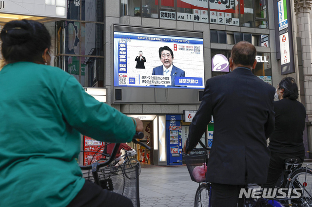 지난 4일 일본 오사카에서 시민들이 아베 신조 총리의 긴급사태 발효 기간 연장 조치 발표를 보고 있다. (출처: 뉴시스)