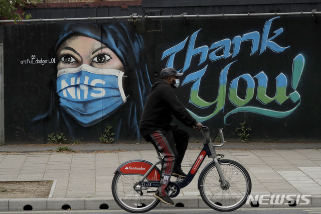 3일(현지시간) 영국 런던에서 신종 코로나바이러스 감염증(코로나19) 예방을 위해 마스크를 쓰고 자전거를 탄 한 남성이 'NHS에 감사' 벽화 앞을 지나고 있다. (출처: 뉴시스)