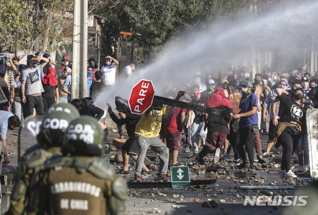 [산티아고=AP/뉴시스] 18일(현지시간) 칠레 산티아고의 한 가난한 동네에서 신종 코로나바이러스 감염증(코로나19)이 유행하고 있는 가운데 일부 시위자들이 정부에 식량 지원을 요구하는 시위 도중 경찰과 충돌하고 있다.