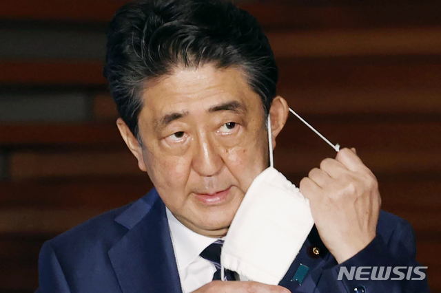 아베 신조 일본 총리가 21일 기자회견에서 마스크를 벗고 있다. 일본 정부는 이날 3개 지역에 대해 긴급사태 선언 추가 해제를 발표했다. 도쿄 등 5개 지역에 대해서는 오는 25일 다시 검토하겠다고 밝혔다(출처: 뉴시스)
