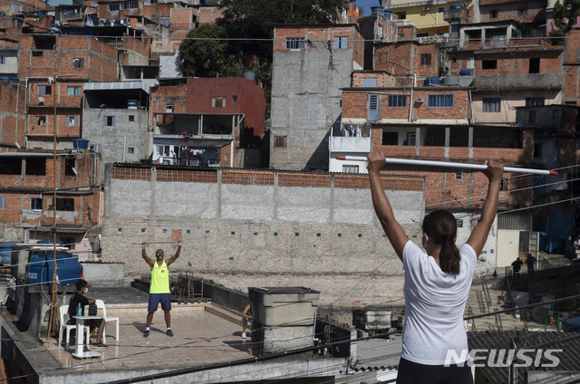 17일(현지시간) 브라질 상파울루 인근 브라질란지아에서 신종 코로나바이러스 감염증(코로나19) 격리 기간 중 체력 단련사 이반 아시멘토(왼쪽)가 자신의 집 옥상에서 이웃들에게 야외 운동 수업을 하고 있다(출처: 뉴시스)