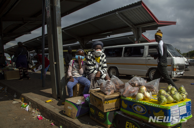 남아프리카공화국 요하네스버그 남쪽 레나시아의 택시 정류장에서 지난 8일 신종 코로나바이러스 감염증(코로나19) 방지를 위해 마스크를 쓴 한 여성과 딸이 과일과 채소를 팔고 있다. (출처: 뉴시스)