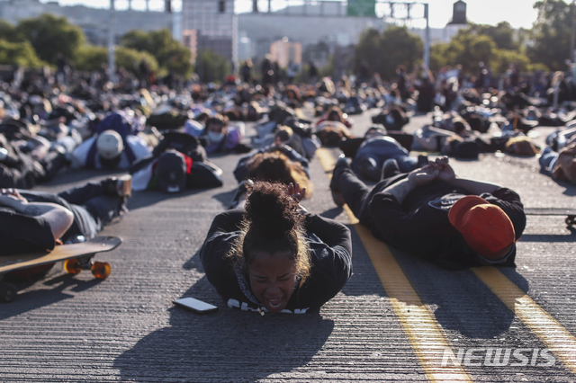 [포틀랜드=AP/뉴시스]지난 1일 오리건 포틀랜드에서 조지 플로이드 사망 항의 시위 참석자들이 손을 뒤로 하고 땅에 엎드려 플로이드 사망 당시 모습을 재연하고 있다.