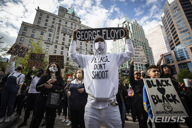 5월 31일(현지시간) 캐나다 밴쿠버에서 미국 흑인 청년 조지 플로이드의 죽음에 항의하는 시위가 열린 가운데 한 남성이 자신의 스케이트보드에 조지 플로이드의 이름을 써 들고 시위에 참여하고 있다. 이날 수천 명이 모여 인종차별과 불공정, 경찰의 만행에 항의하며 시위를 벌였다. (출처: 뉴시스)