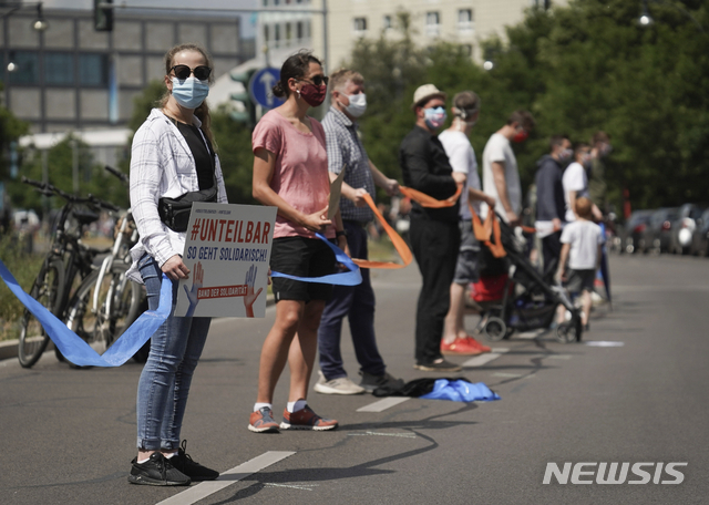 14일(현지시간) 독일 베를린 브란덴부르크문 앞에서 인종차별 반대 시위 참가자들이 마스크를 쓰고 인간사슬을 만들고 있다. [뉴시스/AP]
