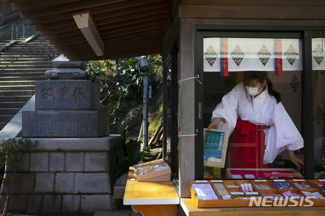 [후지사와=AP/뉴시스] 지난 2월 27일 일본 나가사키현 후지사와의 에노시마 신사 기념품 판매장에서 마스크를 쓴 이곳 직원이 제품을 진열하고 있다.