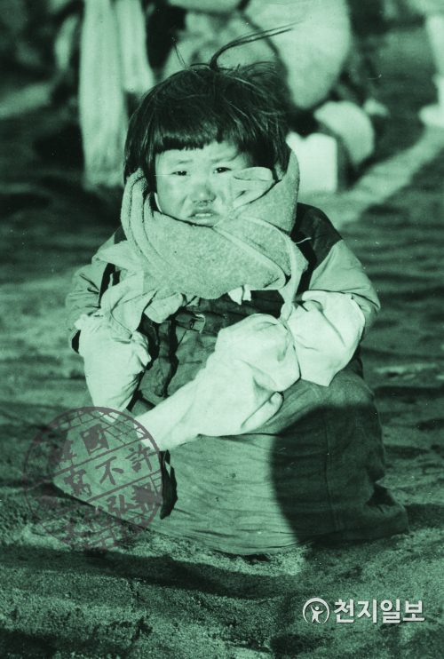 어린 아이가 보는 전쟁(1950년 12월 11일). 이 작은 한국인 아이는 중국 공산군의 공격을 피하기 위해 북한의 수도인 평양에서 대동강을 건너 피해온 피란민 중 하나였다. 엄마 버선을 손에 끼고 있다. (제공: 정성길 명예박물관장) ⓒ천지일보 2020.6.25