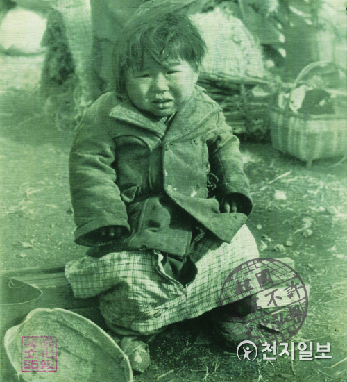 추위와 굶주림에 울고 있는 피란민 아이(1951년 1월 16일). 제발 좀 도와주세요! 이 어린 소녀는 얼마나 이동하였을까? 누더기 옷을 입고 추위와 굶주림에 부산의 부두 위에 앉아서 울고 있는 한 한국인 피란민 아이. 끊임없는 피란이 끝나기만 기다리고 있다. (제공: 정성길 명예박물관장) ⓒ천지일보 2020.6.25