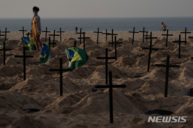 브라질 리우데자네이루의 코파카바나 해변에 11일 자이르 보우소나루 대통령의 신종 코로나바이러스 감염증(코로나19) 대응에 항의하는 100개의 모조 무덤이 인권운동가들에 의해 만들어진 가운데 한 여성이 검은 십자가들이 세워진 무덤들 사이를 걷고 있다(출처: 뉴시스)