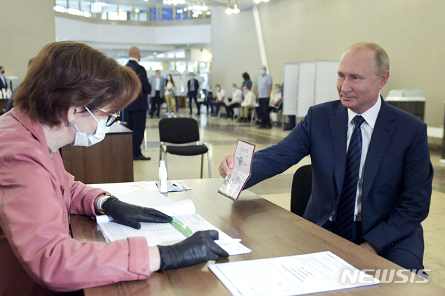 [모스크바=AP/뉴시스]블라디미르 푸틴 러시아 대통령이 1일(현지시간) 러시아 모스크바의 한 투표소에 도착해 신원 확인을 위해 선거관리위원회 관계자에게 여권을 보여주고 있다. 이날 러시아에서 푸틴 대통령의 장기집권을 터줄 헌법 개정 국민투표 본 투표가 열렸다.