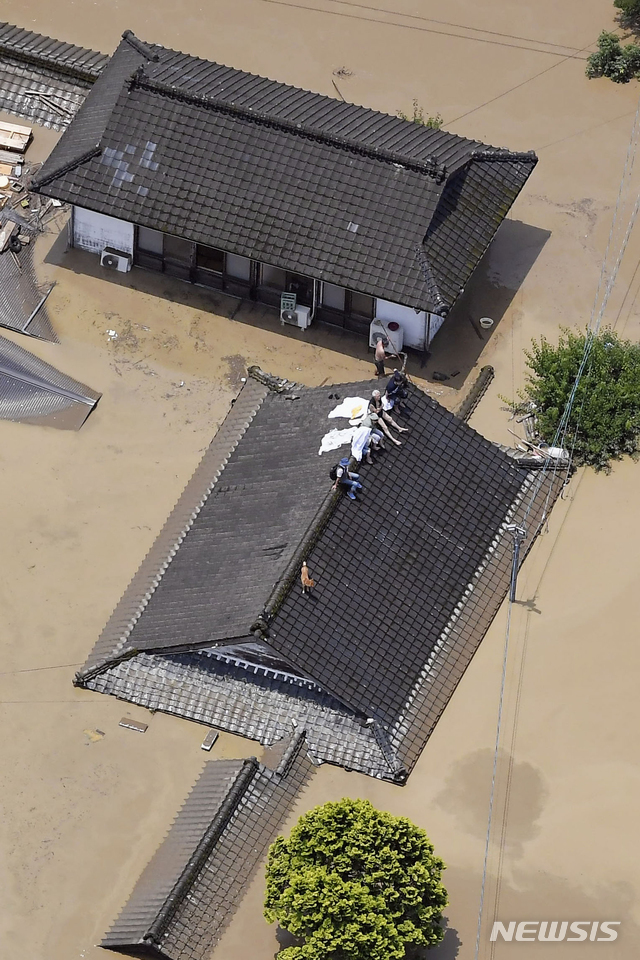 4일 일본 규슈지역 구마모토현 히토요시시에서 폭우로 가옥이 물에 잠기자 주민들이 지붕 위에 올라가 구조를 기다리고 있다. (히토요시(일본 구마모토현)=AP/뉴시스)