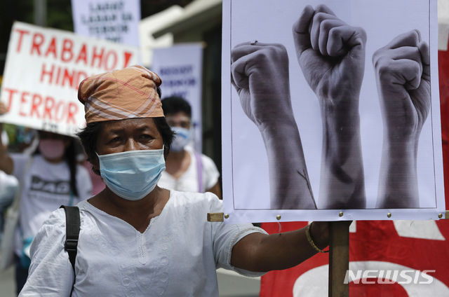 7일(현지시간) 필리핀 수도 마닐라의 필리핀 국립대에서 테러방지법 반대 집회가 열려 마스크를 쓴 한 여성이 주먹이 그려진 손팻말을 들고 있다. 시위대는 로드리고 두테르테 대통령이 최근 서명한 테러방지법에 인권침해 소지가 있다며 반대하고 있다. (출처: AP/뉴시스)