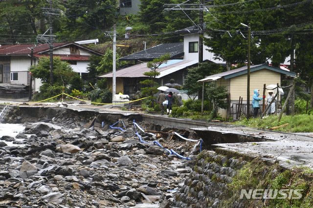 10일 일본 기후현 다카야마에서 주민들이 호우로 유실된 도로를 걷고 있다. 일본 일부 지역에서 실종자 수색 작업과 복구 작업이 이어지는 가운데 관계 당국은 이번 주말 더 많은 비가 내릴 것에 대비하고 있다. (출처: 뉴시스)