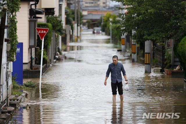 7일 일본 후쿠오카현 오무타에 내린 폭우로 한 남성이 침수된 도로를 헤쳐나가고 있다. 일본 남부에 내린 기록적인 폭우로 곳곳에서 홍수 피해가 속출하고 있다. (출처: 뉴시스)