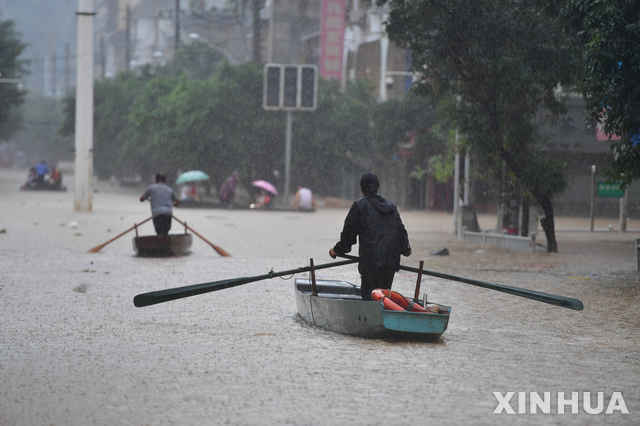 [광시=AP/뉴시스] 12일 중국에서 홍수가 계속되는 가운데 광시 좡족 자치구에서 물로 가득찬 거리를 사람들이 배를 타고 건너고 있다. 2020.07.12. (출처: 뉴시스)