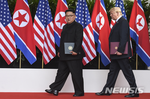 김정은 북한 국무위원장(왼쪽)과 도널드 트럼프 미 대통령이 지난 2018년 6월 12일 싱가포르 센토사섬의 카펠라 호텔에서 첫 북미 정상회담 후 합의문에 조인한 뒤 각자 서명한 합의문을 들고 퇴장하고 있다. (출처: 싱가포르=AP/뉴시스)