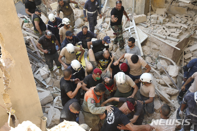 레바논 베이루트에서 5일(현지시간) 시민들이 전날 발생한 폭발참사로 무너진 건물더미에서 생존자를 구해내 밖으로 옮기고 있다(출처: 뉴시스)