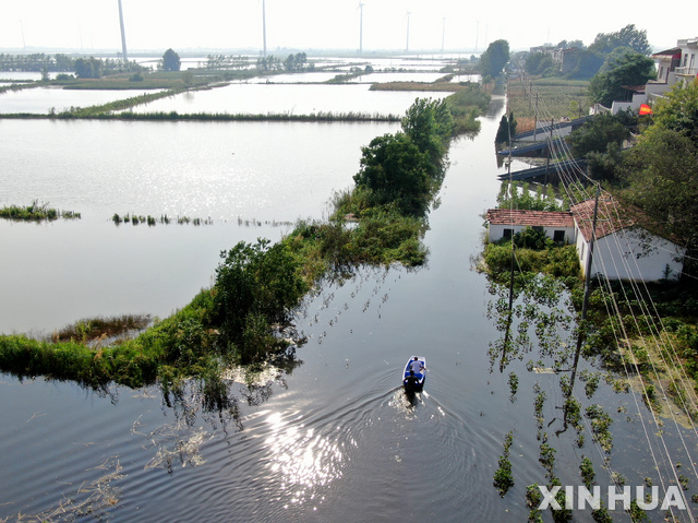 지난달 18일 중국 장시성 주장의 한 마을이 홍수로 침수된 가운데 한 부자(父子)가 뗏목을 타고 지나가고 있다. (출처: 뉴시스)