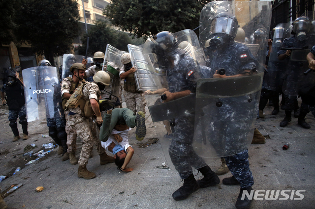 8일(현지시간) 레바논 베이루트에서 반정부 시위가 열린 가운데 한 시위 참가자가 경찰에게 포위당하고 있다. (출처: 뉴시스)