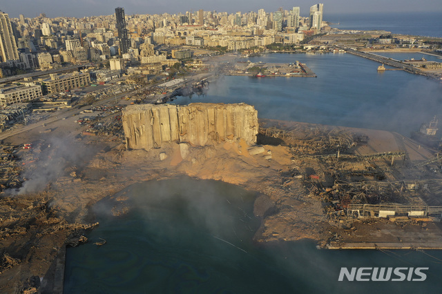 레바논 베이루트 항구에서 폭발사건이 발생한 다음 날인 5일(현지시간)에도 연기가 피어오르고 있다. 초대형 폭발로 파괴된 창고 건물의 일부가 서있고, 그 앞의 땅이 분화구처럼 함몰돼있는 것이 보인다.  (출처: 뉴시스)