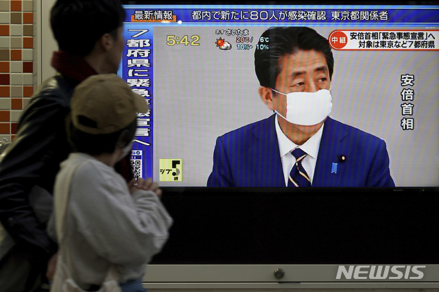 아베 신조 일본 총리가 7일 신종 코로나바이러스 감염증(코로나19) 확산을 막기 위해 도쿄 등 7개 지역에 긴급사태 선언을 발령한 가운데, 도쿄 거리의 시민들이 지나가면서 TV를 통해 관련 보도를 보고 있다(출처: 뉴시스)