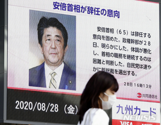 28일 일본 후쿠오카에서 아베 신조 일본 총리가 사임할 것이라는 뉴스 화면 앞을 한 여성이 지나고 있다. (출처: 뉴시스)