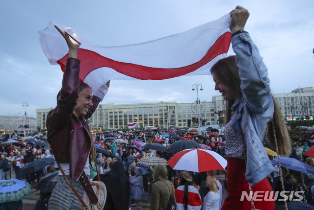 26일(현지시간) 벨라루스 수도 민스크에서 벨라루스 야당 지지 집회가 열린 가운데 참가자들이 옛 벨라루스 국기를 들고 있다(출처: 뉴시스)