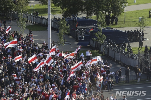 13일(현지시간) 벨라루스 수도 민스크에서 시위대가 국기를 들고 시위를 벌이고 있다. 벨라루스에서 지난달 치러진 대선 결과에 불복하는 야권 시위가 한 달 이상 이어지고 있다. (출처: 뉴시스)