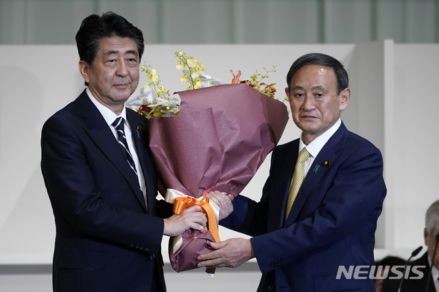 14일 일본 자민당이 스가 요시히데 관방장관(오른쪽)을 차기 총재로 뽑은 가운데 아베 신조 일본 총리(왼쪽)가 꽃을 건내며 축하하고 있다. (출처: 뉴시스)