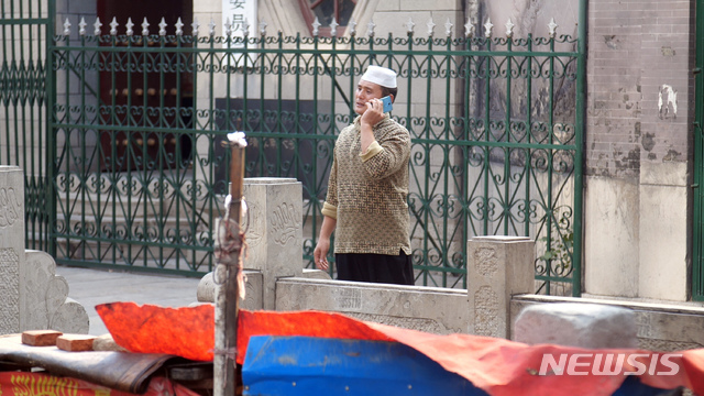 【지난=AP/뉴시스】 2018년 9월27일 중국 산둥성 지난 난다시 모스크 앞에서 한 중국인 무슬림이 전화 통화를 하고 있다.