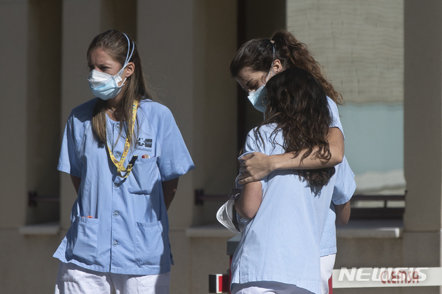 5일(현지시간) 스페인 마드리드의 한 병원 밖에서 휴식을 취하던 한 의료 종사자가 동료를 안아주고 있다(출처: 뉴시스)