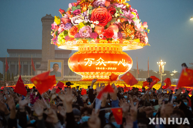 [베이징=신화/뉴시스] 중국 베이징 톈안먼 광장에서 1일 공산중국 수립을 축하하는 국경절을 맞아 열린 오성홍기 게양식을 지켜보기 위해 몰린 군중이 기념 조형물에 불이 들어오자 작은 깃발을 흔들며 환호하고 있다.