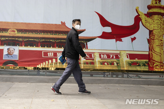 [우한=AP/뉴시스] 지난 4월 16일(현지시간) 신종 코로나바이러스 감염증(코로나19) 발원지인 중국 후베이성 우한시에서 마스크를 낀 한 남성이 정부 선전물 앞을 지나고 있다.