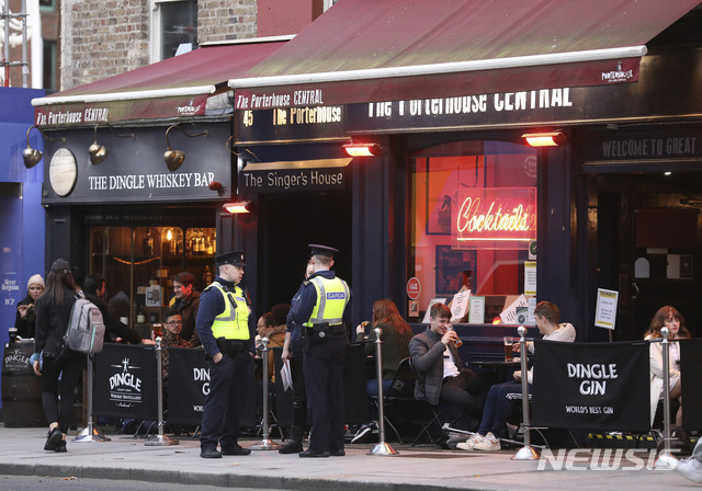 21일(현지시간) 아일랜드 더블린의 한 술집 밖에 마스크를 쓰지 않은 사람들이 앉아 있다. (출처: 뉴시스)