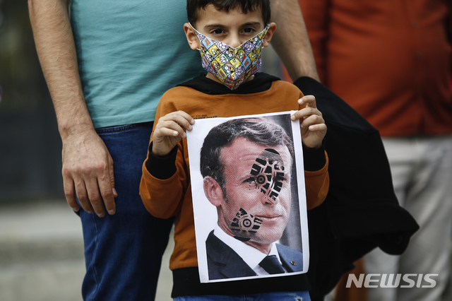 [이스탄불=AP/뉴시스]25일(현지시간) 터키 이스탄불에서 한 어린이가 프랑스에 대한 항의 시위 도중 신발 자국이 찍힌 에마뉘엘 마크롱 프랑스 대통령의 사진을 들고 있다. 레제프 타이이프 에르도안 터키 대통령은 마크롱 대통령에 대해 연이틀 