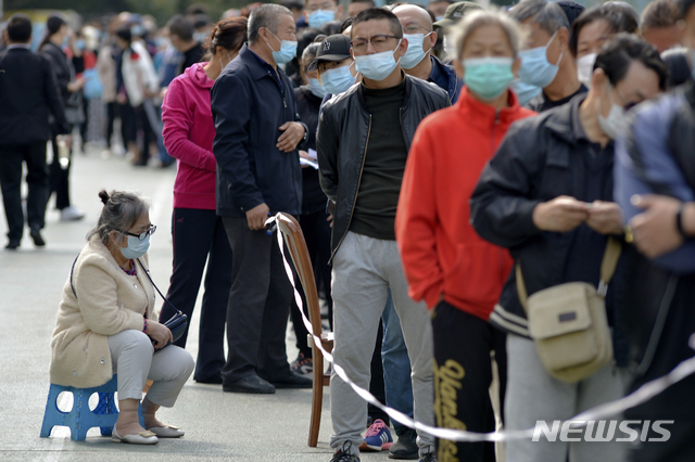 10월 12일(현지시간) 중국 산둥성 동부의 칭다오 주택가 인근에서 코로나19 확산 예방을 위해 마스크를 쓴 주민들이 코로나19 검사를 받기 위해 줄 서서 기다리고 있다(출처: 뉴시스)