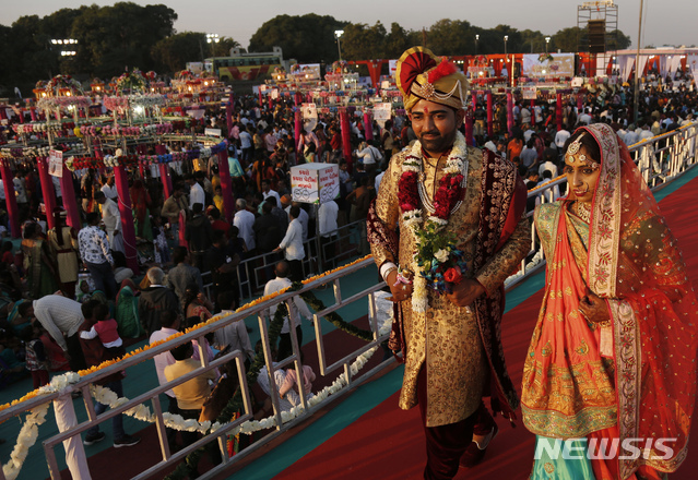 【수라트=AP/뉴시스】23일(현지시간) 인도 수라트에서 합동결혼식이 열려 한 커플이 함께 걷고 있다.