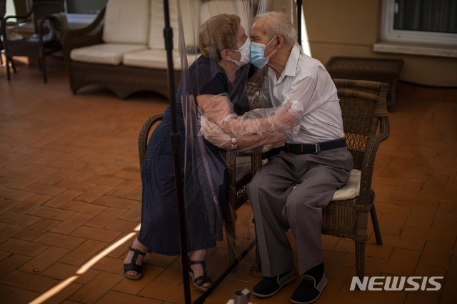 2020년 6월 22일. 아구스티나 카나메로(81)와 파스구알 페레스(84)가 스페인 바르셀로나의 한 요양원에서 코로나19 감염을 피하기 위해 플라스틱 스크린을 통해 포옹과 키스를 하고 있다. (출처: 뉴시스/AP)