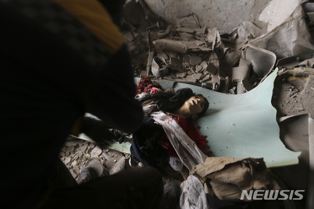 2020년 2월 11일 시리아 이들리브에서 정부군 공습으로 사망한 소년의 시신을 응급 구조대가 들고 있다. (출처: 뉴시스/AP)