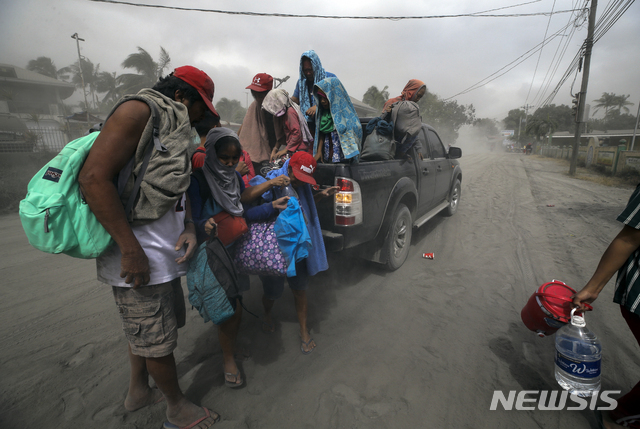 2020년 1월 13일 필리핀 남부 바탕가스의 레메리에서 타알화산이 재를 뿜어내자 한 가족이 대피하고 있다. (출처: 뉴시스/AP)
