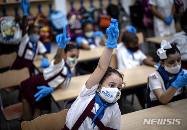 11월 2일 쿠바 아바나에서 마스크와 장갑을 낀 소녀들이 수업 중 손을 들고 있다. 코로나19 유행으로 4월 당국이 이 섬을 폐쇄한 이후 처음으로 학생들이 학교에서 대면 수업에 복귀했다. (출처: 뉴시스/AP)
