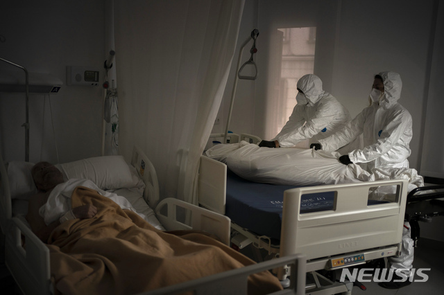 11월 5일 스페인 바로셀로나 요양원에서 한 환자가 침대에서 잠을 자는 가운데 옆에서는 코로나19로 숨진 환자의 시신을 옮기고 있다. (출처: 뉴시스/AP)