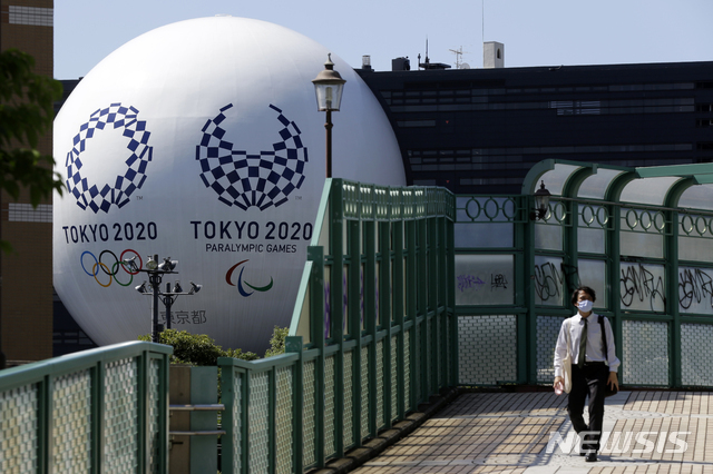 지난 9월 일본 도쿄에서 2020 도쿄 올림픽과 패럴림픽 대형 조형물을 뒤로 한 남성이 철로 위를 걷고 있다.