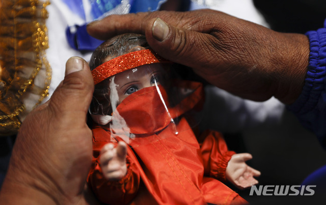 9일(현지시간) 볼리비아 라파스에서 열린 크리스마스 박람회에서 한 상인이 코로나19 확산 예방 의미로 아기 예수 인형에 마스크와 얼굴 가리개를 씌우고 있다. (출처: AP/뉴시스)
