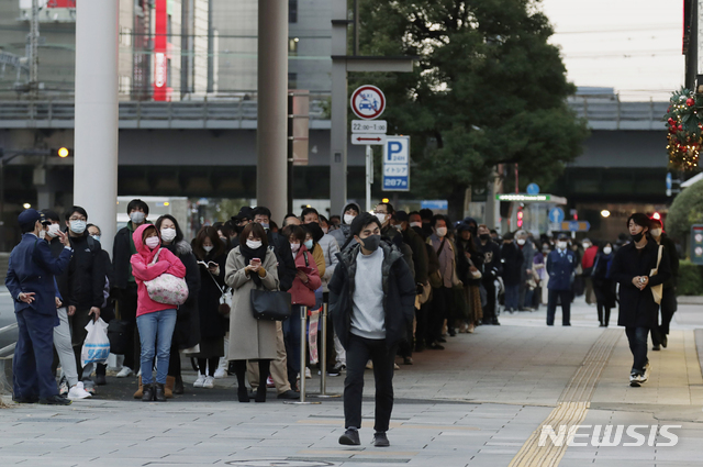 10일(현지시간) 일본 도쿄에서 한 남성(가운데)이 복권을 사기 위해 줄을 서서 기다리는 사람들을 지나쳐 걸어가고 있다(출처: 뉴시스)
